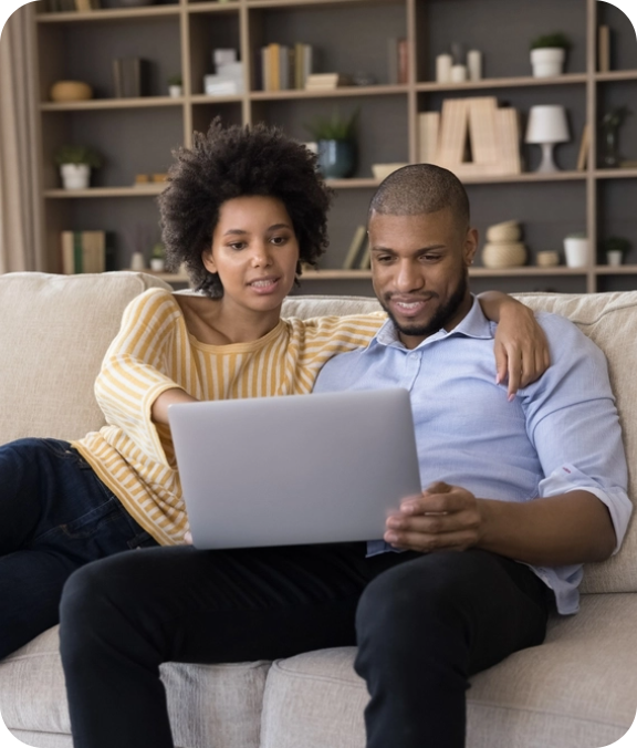 a man and a woman sitting on a couch using a laptop