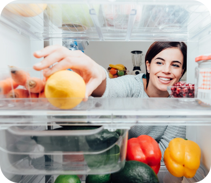 A woman pulling food out of a refrigerator