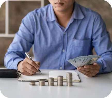 Man writing in book with cash and coins